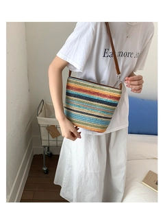 Dettaglio borsa a secchiello intrecciata con strisce arcobaleno e tracolla in pelle