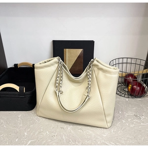 Close-up of beige leather tote bag with lychee texture and silver chain strap detail