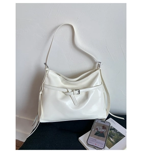 Detail of a minimalist cream white glossy PU leather hobo bag with silver buckle accents