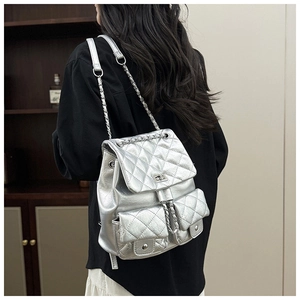 Détail de sac à dos argenté matelassé avec bretelles en chaîne et texture métal