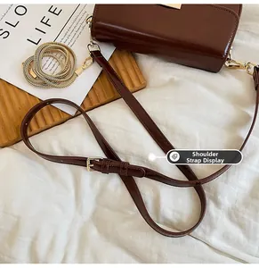 Detail of dark brown leather handbag showing adjustable strap and gold metal chain