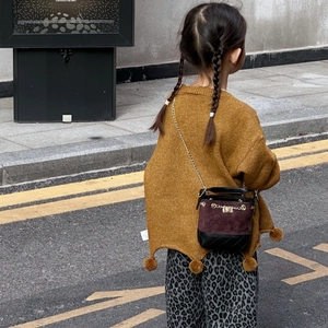 Outdoor shot of kids bucket bag with burgundy faux suede and metal chain strap details
