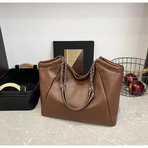 Detail of brown lychee grain leather tote bag with silver chain and leather handles