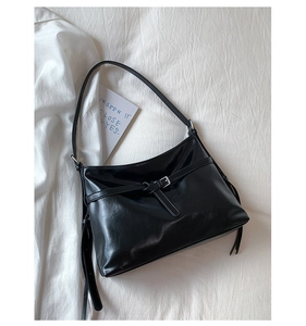 Close-up of black PU leather shoulder bag with silver buckle and decorative tassels