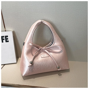 Close-up of pink metallic handbag with bow detail and black white striped lining