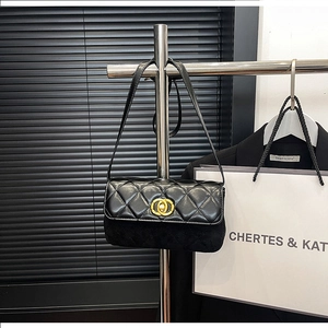 Detail of black quilted shoulder bag featuring mixed leather texture and golden metal lock