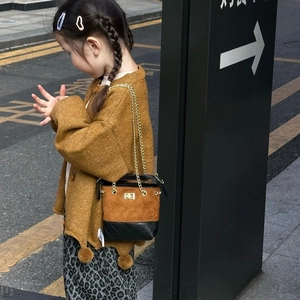 Detail view of children's bucket bag with contrast stitching and gold chain strap