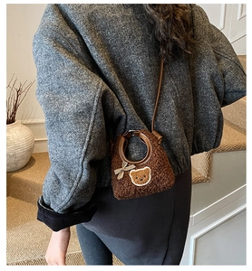 Gros plan d'un sac à main peluche marron avec nœud porté sur un manteau en tweed