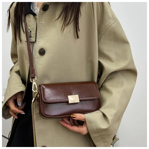 Detail of a brown oil wax leather crossbody bag featuring a golden square metal buckle