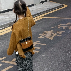Outdoor street style view of a girl wearing a brown knit sweater and mini crossbody bag
