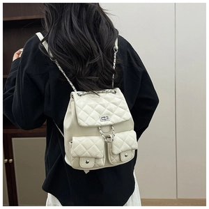Gros plan du sac à dos matelassé crème avec bretelles en chaîne et boucle rotative en métal