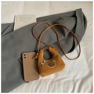 Détail du petit sac bandoulière en peluche marron avec tête d'ours brodée et nœud à carreaux