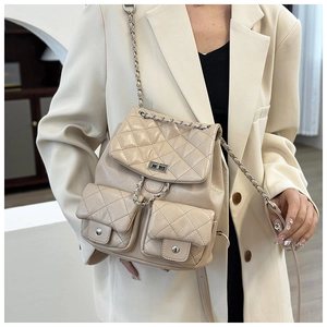 Petit sac à dos beige matelassé avec chaîne argentée sur une tenue de blazer blanc