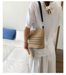 Dettaglio borsa a tracolla in paglia intrecciata beige con righe nere e cinturino