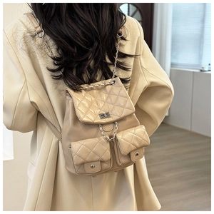 Détail du sac à dos matelassé beige avec bretelles en chaîne métallique et fermoir rotatif