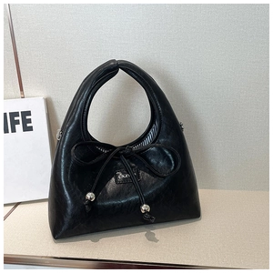 Close-up of black PU leather handbag featuring decorative bow and metallic beads detail
