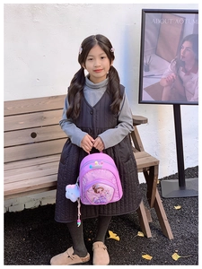 Girl wearing a purple princess sequin backpack with a cute pompom pendant outdoors