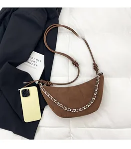 Detail view of a brown suede crescent bag with silver chain and knotted shoulder strap