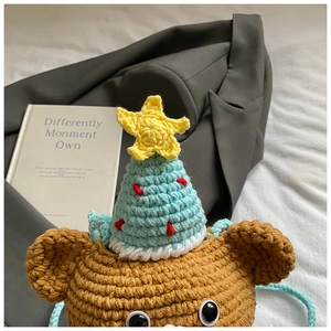 Detailed knit texture of handmade bear crossbody bag with festive Christmas tree hat decoration