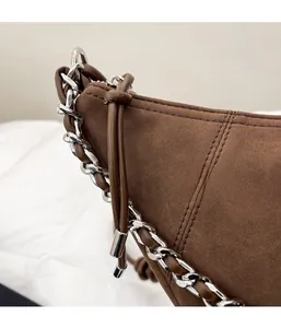 Detail of dark brown suede handbag featuring a thick silver chain and premium stitching