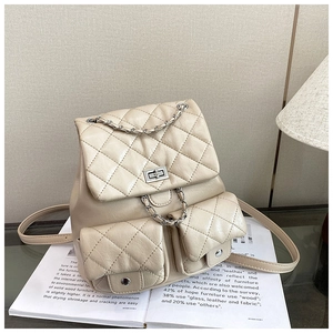 Vue détaillée du sac à dos matelassé beige avec chaîne argentée et deux poches avant
