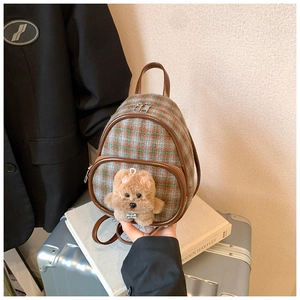 Detailed view of mini plaid backpack featuring a plush puppy charm and faux leather trim