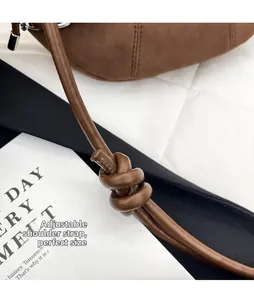 Detail of adjustable knotted shoulder strap on brown suede hobo bag with metal buckle