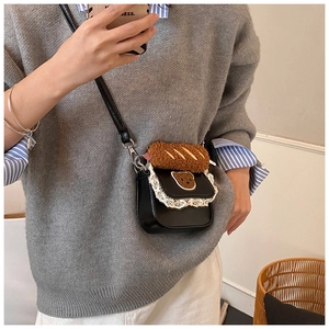 Detail of mini black crossbody bag featuring lace trim, bear embroidery and plush bread charm