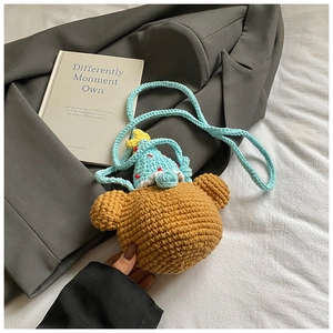Detailed view of handmade crochet bear bag with party hat on a soft textured background