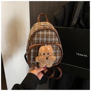 Detail of checkered mini kids backpack with brown leather handle and cute plush dog pendant