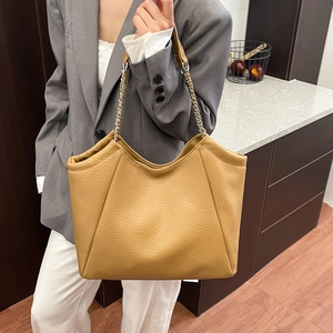 Caramel large capacity leather tote bag with silver chain strap shown on model's shoulder