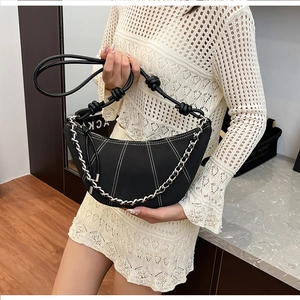 Détail du sac croissant noir avec surpiqûres blanches et bandoulière en chaîne argent