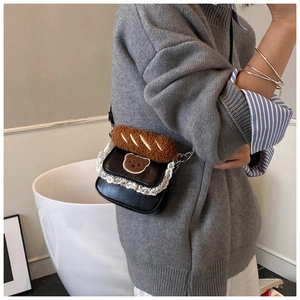 Detail of mini black crossbody bag with lace trim and plush baguette toy decoration