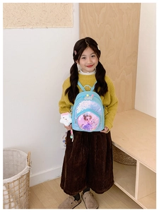 Close-up of sky blue sequin backpack with unicorn print worn by a little girl