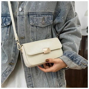 Detail of cream white faux leather shoulder bag with elegant gold metal twist lock