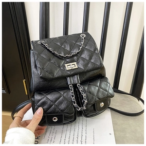 Détail d'un sac à dos en cuir noir matelassé avec chaîne argentée et fermoir pivotant