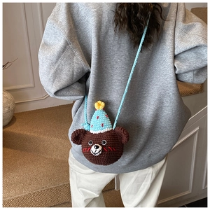 Close-up of a handmade crochet bear crossbody bag with a blue party hat detail