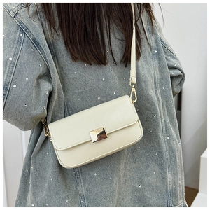 Detail of a creamy white leather shoulder bag with a polished gold metallic buckle