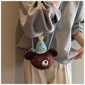 Detailed view of a hand-knitted brown bear crossbody bag with a blue party hat accessory