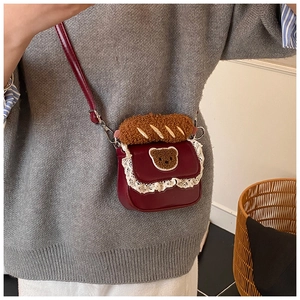 Detail view of red mini crossbody bag with delicate white lace trim and plush bear ornament