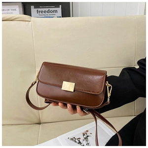 Detailed close-up of brown leather shoulder bag with golden rectangular metal clasp