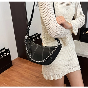 Détail du sac croissant noir avec surpiqûres blanches et chaîne métallique argentée