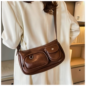 Detail of vintage brown PU leather shoulder bag with zipper and flap pockets on front