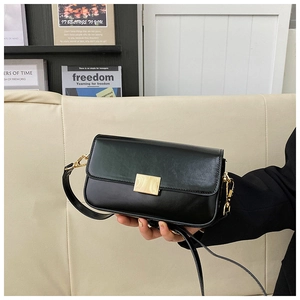 Detail of elegant black leather crossbody bag with gold rectangular metal lock closure
