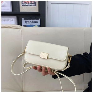 Detail of elegant beige square shoulder bag featuring a sleek golden rectangular metal clasp