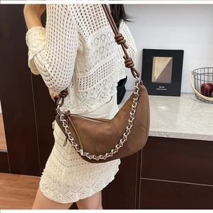 Détail du sac demi-lune en daim marron avec chaîne en métal argenté et bandoulière