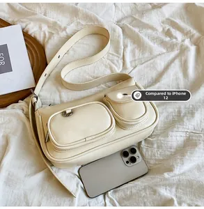 Detail of cream multi-pocket crossbody bag shown with iPhone 12 for size comparison
