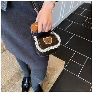 Detail of mini brown bear bag with lace trim and plush handle in a lifestyle setting