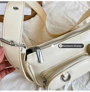 Detailed view of silver zippers and hardware on a beige faux leather underarm bag