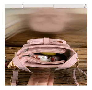 Detail view of pink bow handbag interior with zipper compartment and makeup storage